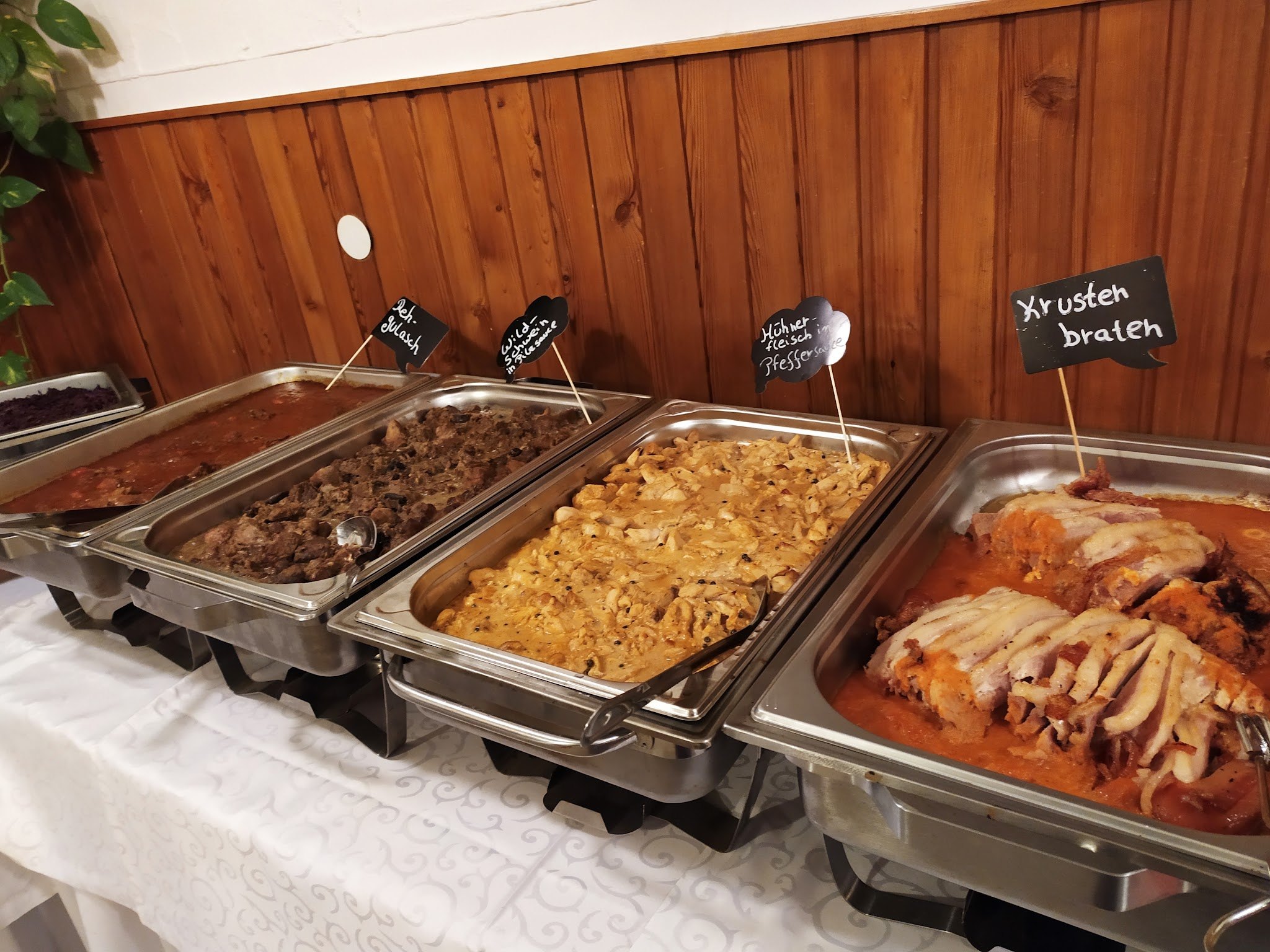 Warmes Buffet in Wärmebehältern, unter anderem Krustenbraten und Kartoffelgratin
