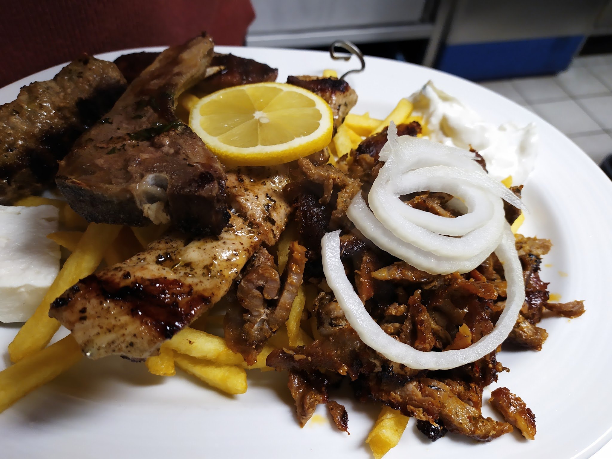 Gyros mit Zwiebelringen, Zitrone und Pommes frites
